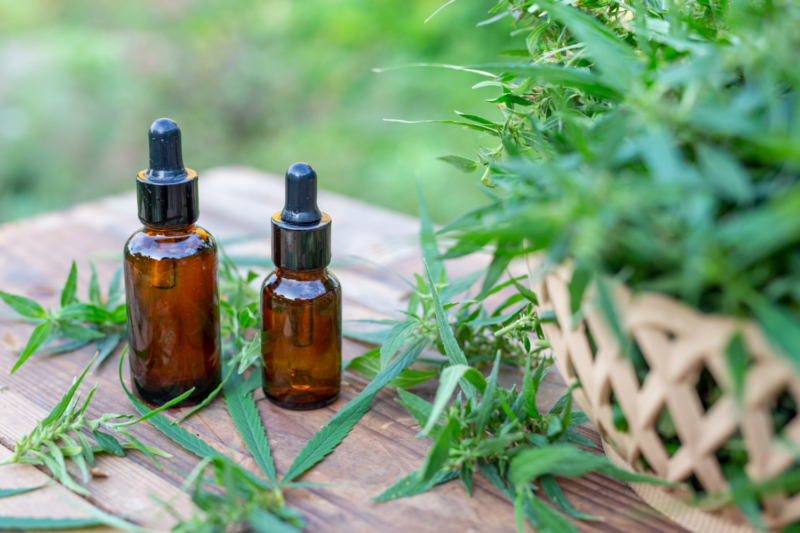 Two cannabis tincture oil bottles with hemp in background