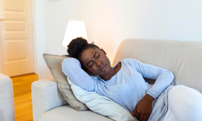 Woman laying on couch with menstrual pain